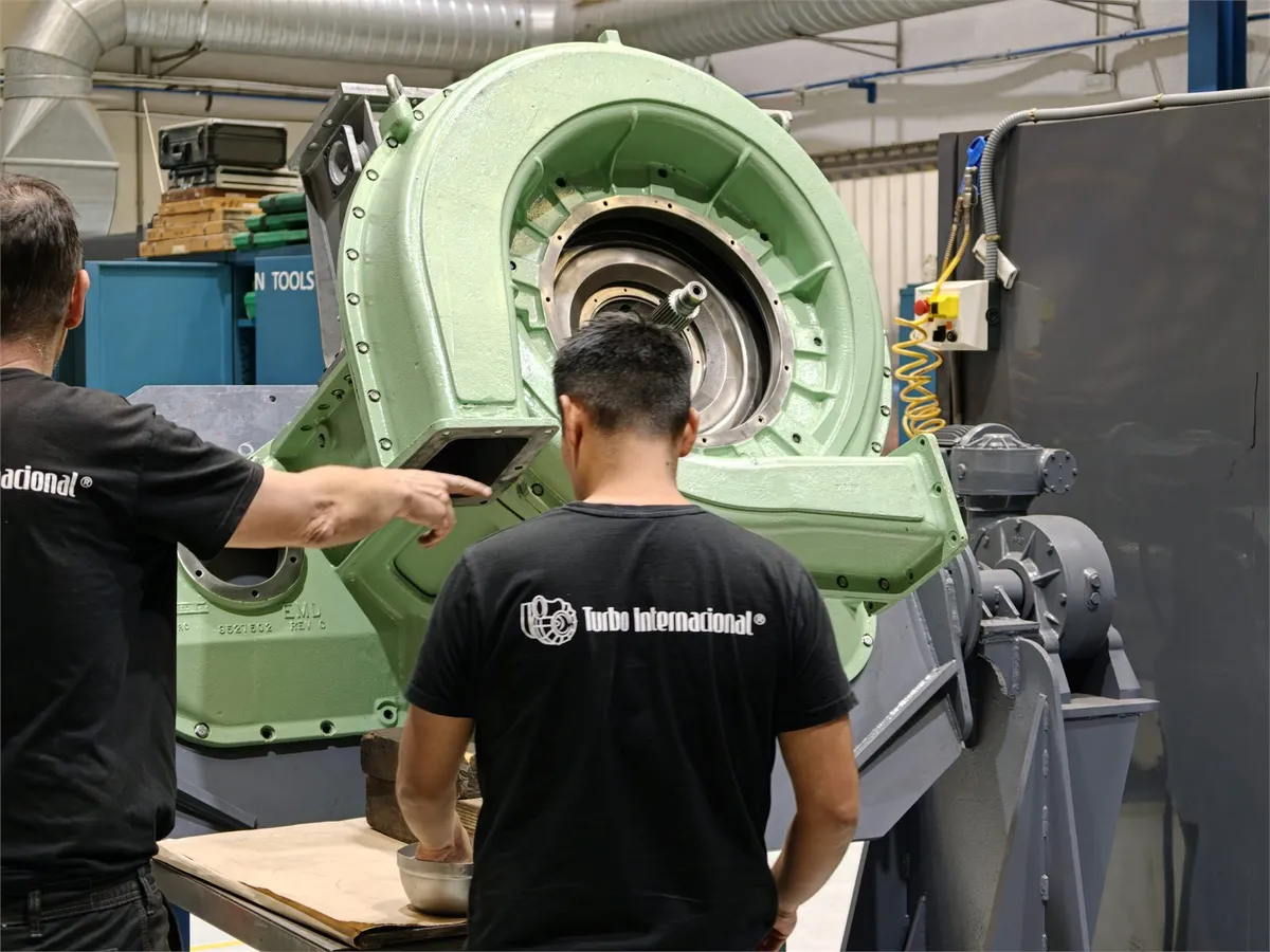 Two Turbo Internacional technicians inspecting an EMD turbocharger housing