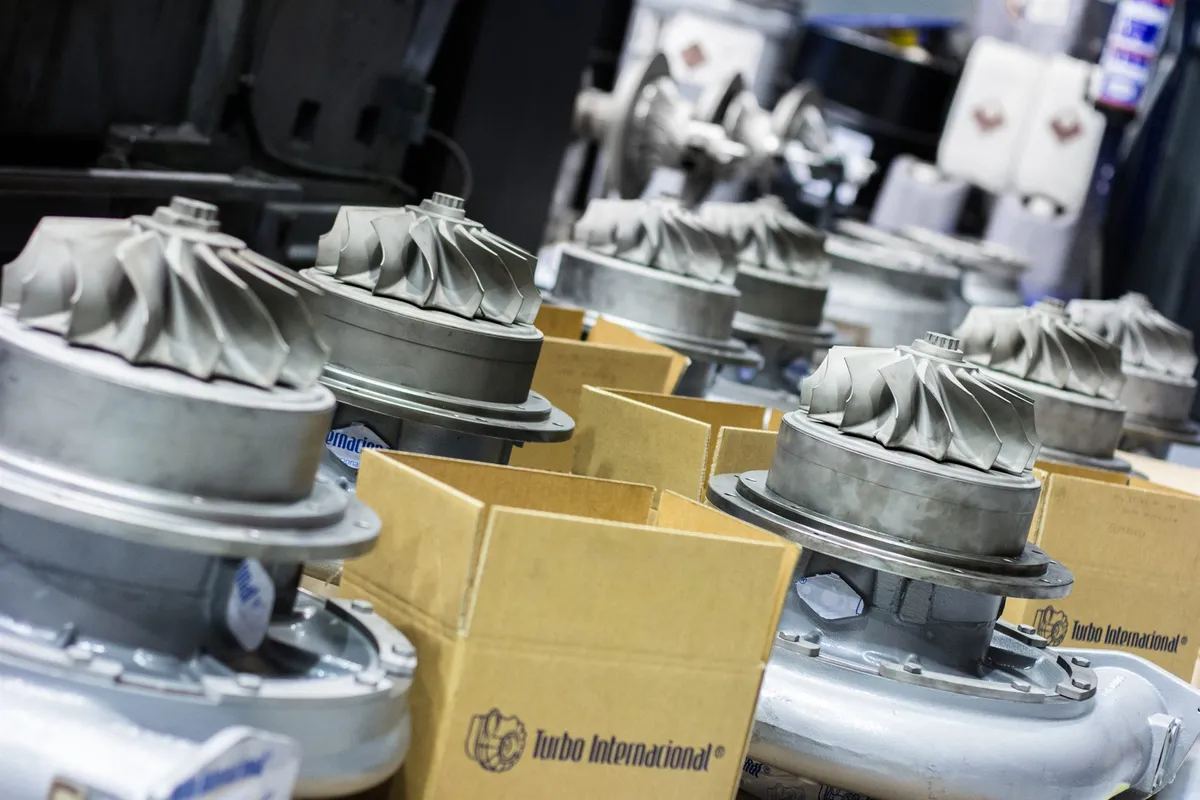 Row of overhauled MTU ZR-275 turbochargers with compressor wheels exposed, beside Turbo Internacional export packing