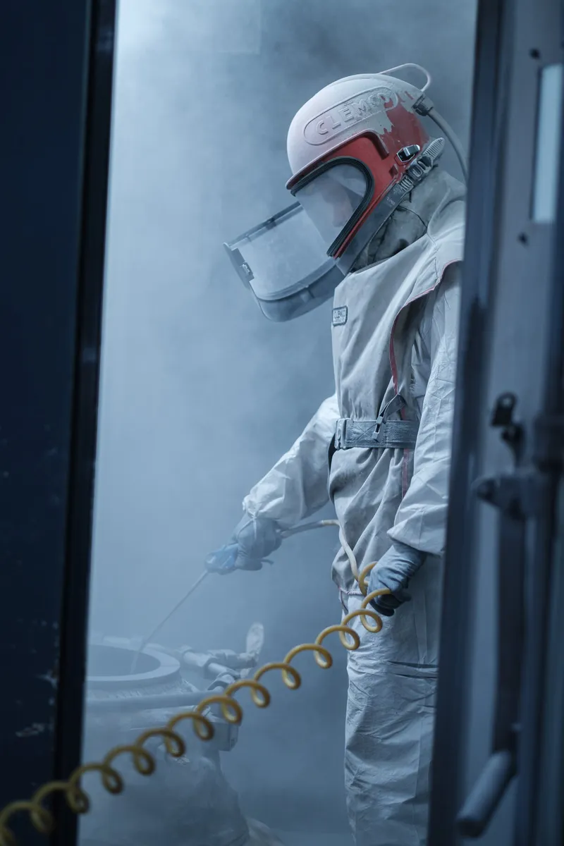 Operator blasting a component inside the blasting cabin