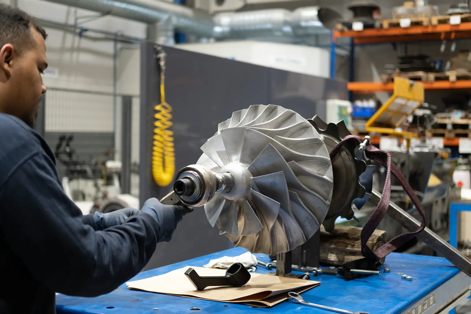 Technician handling a turbocharger rotor at the workshop bench