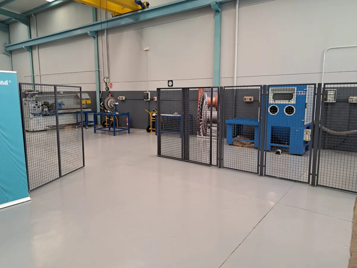 Fenced machine area at the Algeciras workshop, with the blasting cabinet and the overhead crane