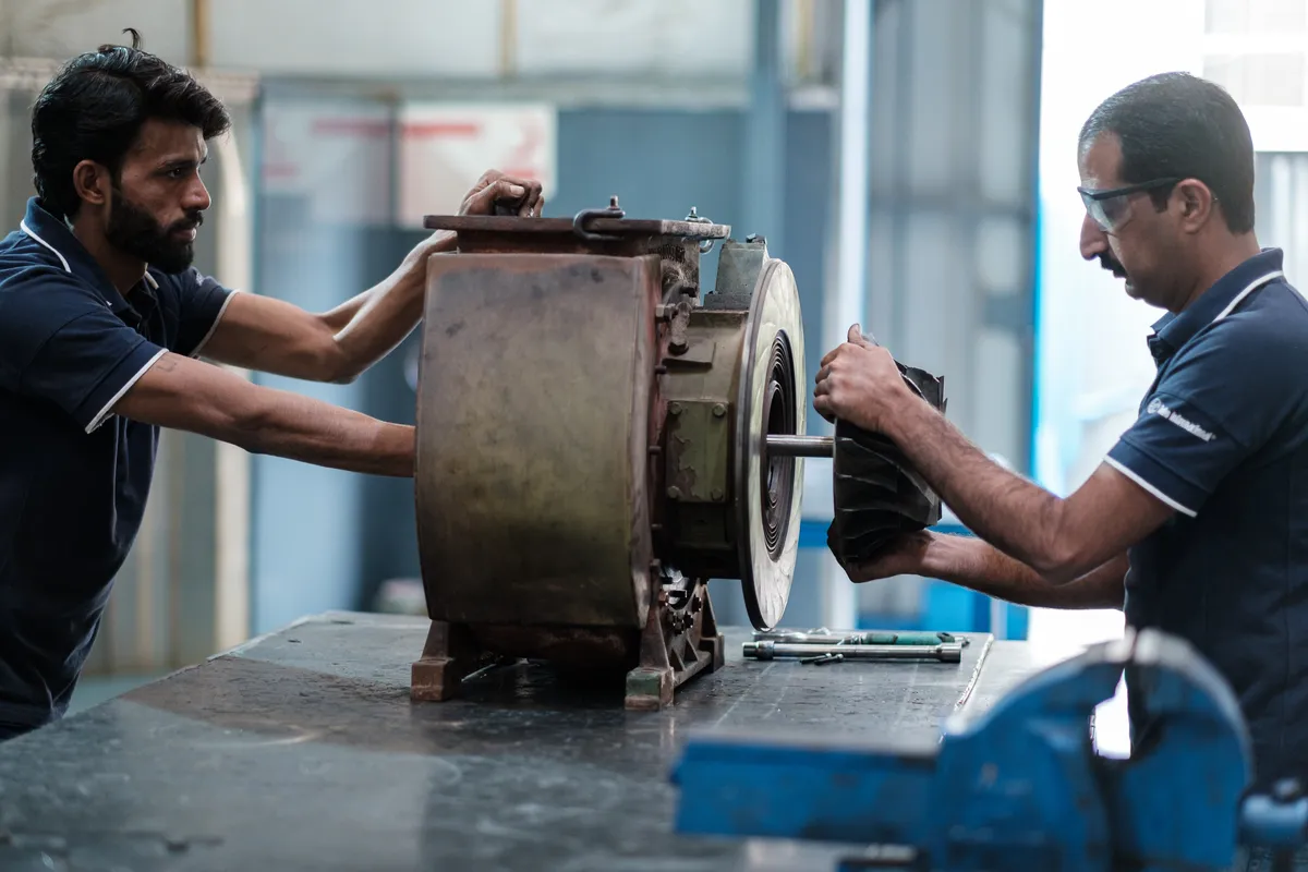 Two technicians stripping down a turbocharger casing at Lahore