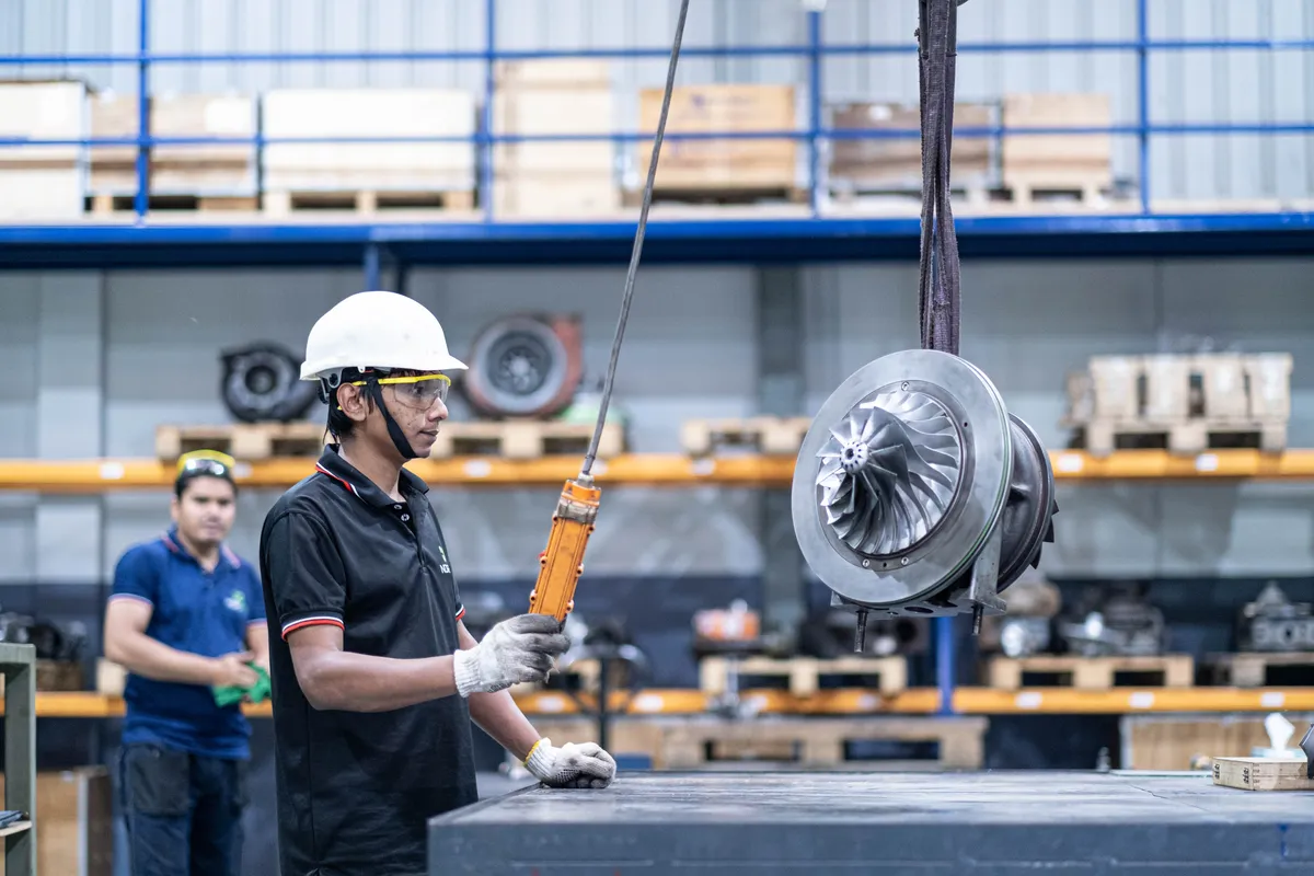 Technician guiding a turbocharger cartridge on the hoist at the Dhaka workshop