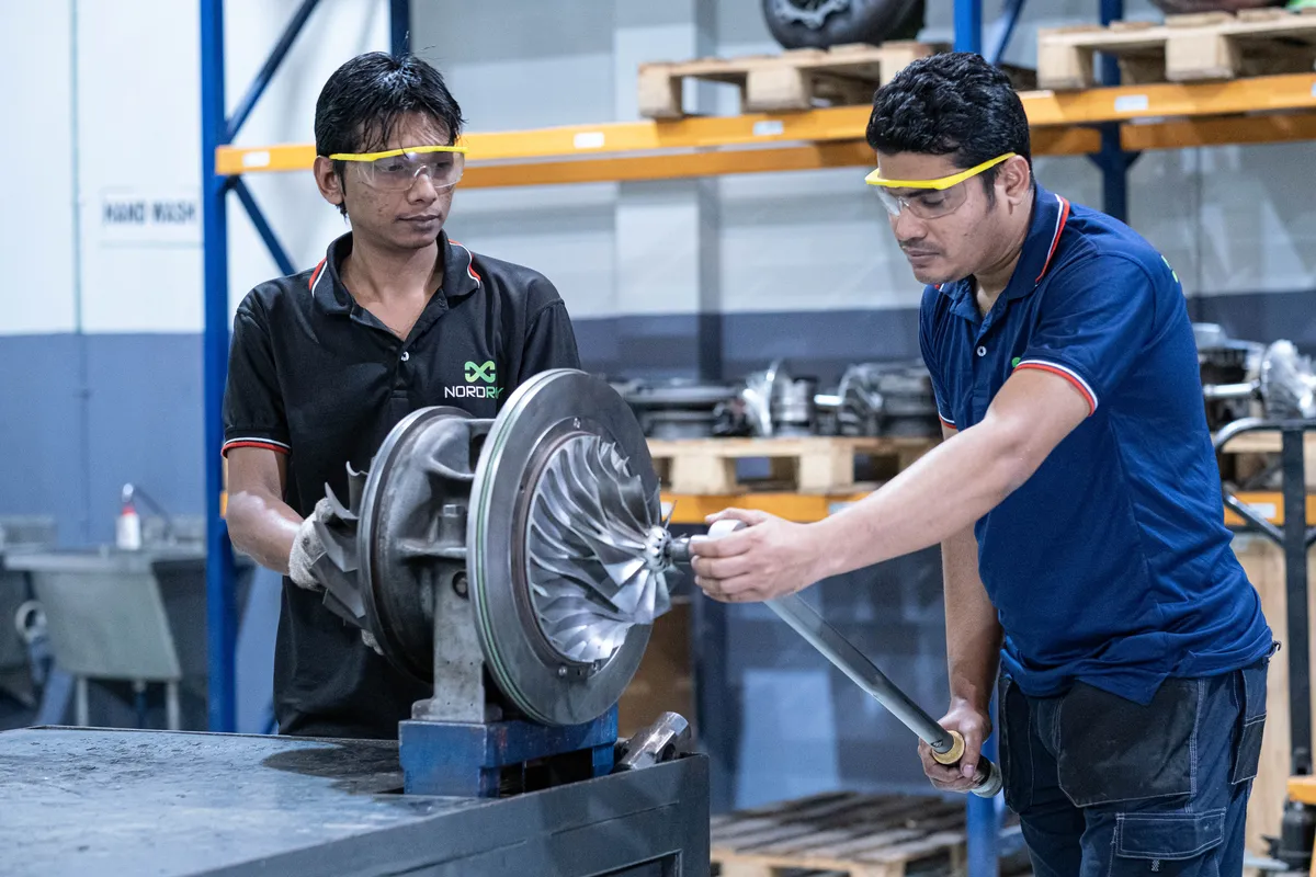 Two technicians torquing a turbocharger rotor assembly at Dhaka
