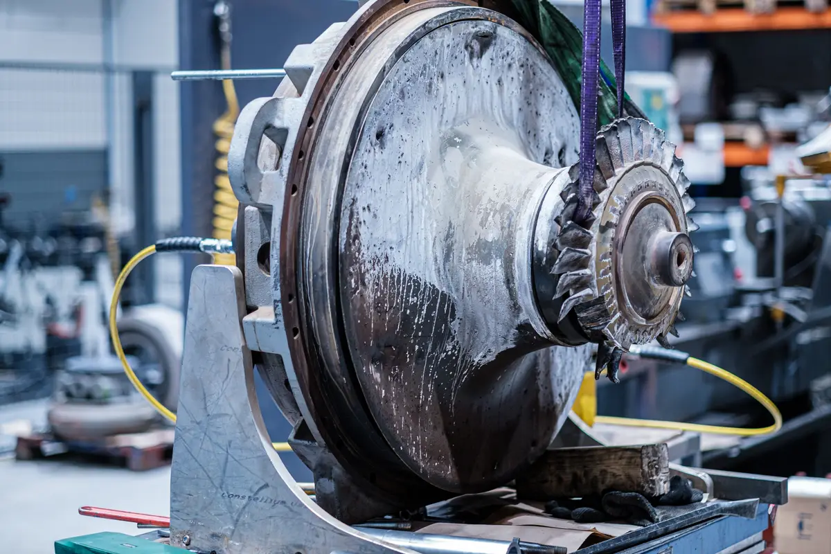 Turbine end of a TPL turbocharger with heavy deposits and damaged blade tips, on a workshop stand for failure inspection